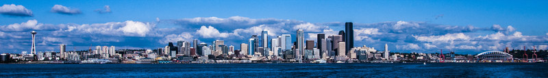 Seattle skyline panorama with the Space Needle and city reflected across Puget Sound under blue skies